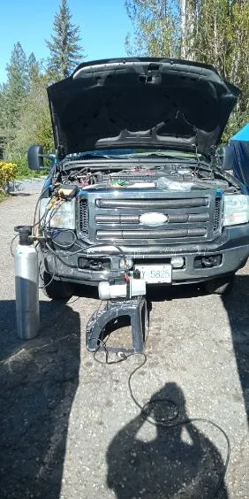 Ford F-250 with hood up and A/C service equipment connected — performed at the owner’s property